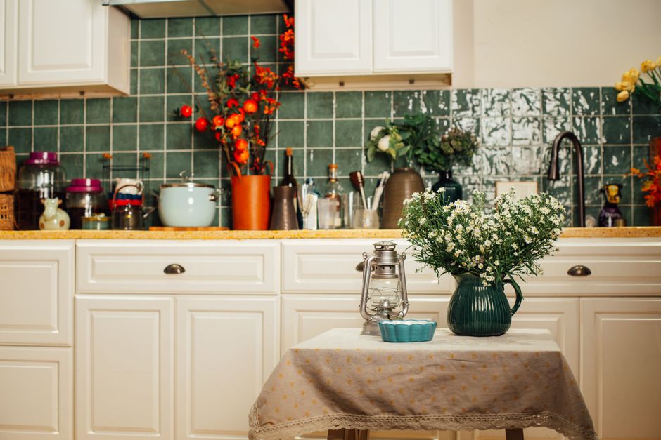 Warm and inviting kitchen scene featuring potted flowers, vintage decor, and classic white cabinets.