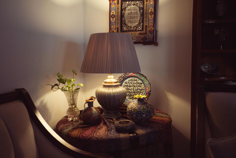 A warm, cozy living room corner with a decorative lamp, ceramics, and art, creating a bohemian atmosphere.